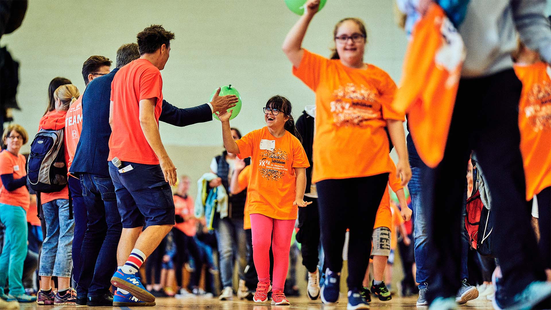 Foto: Mädchen im orangenen Shirt gibt einem Mann auf dem Weg ein High-Five.