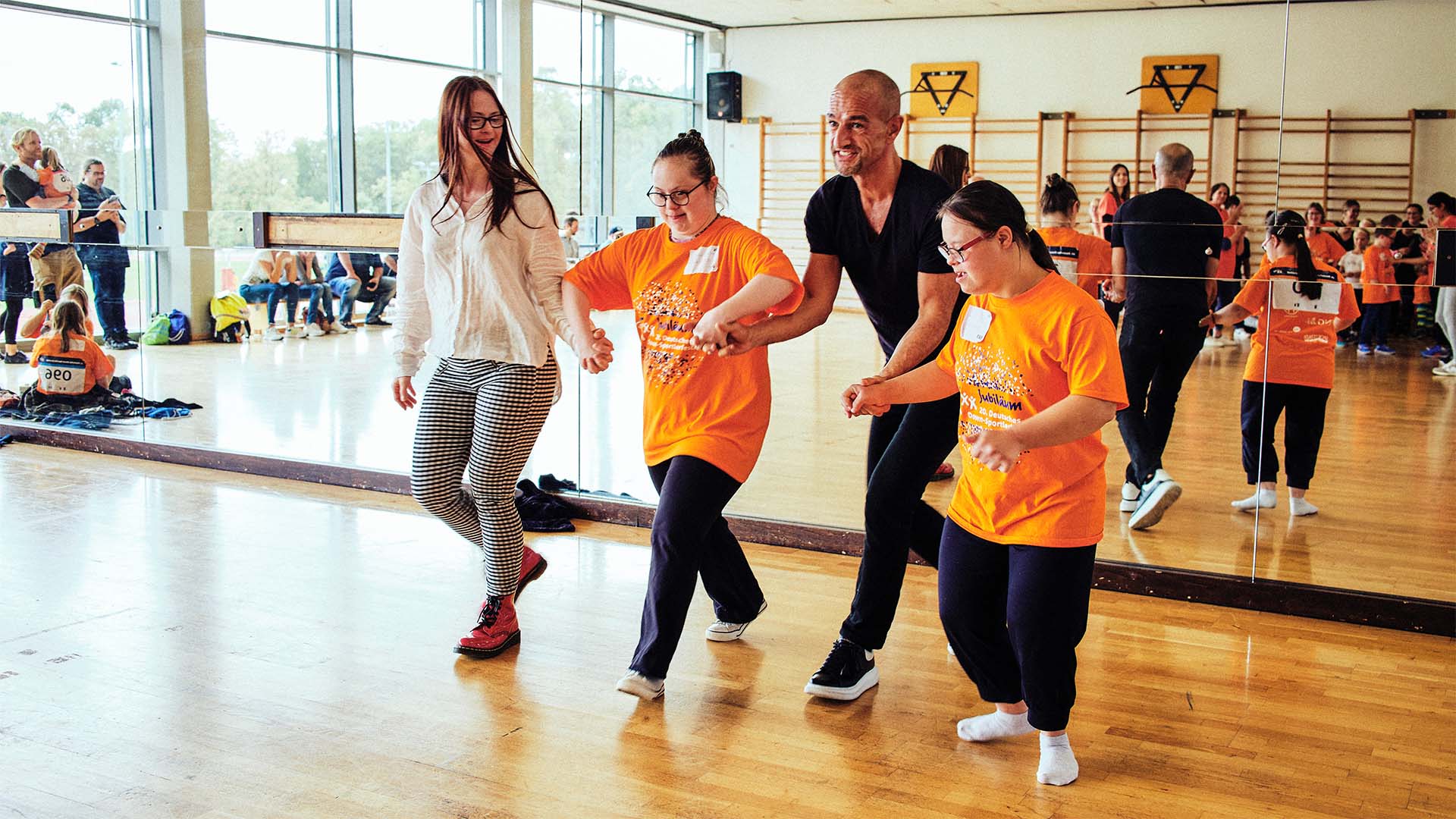 Foto: Gruppe von Teilnehmern tanzt angeleitet von Model Tamara Röske und Coach Peyman Amin.
