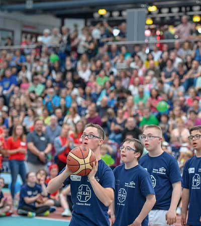 Foto: Junger Mann mit Down-Syndrom mit Basketball in der Hand setzt zum Wurf an.