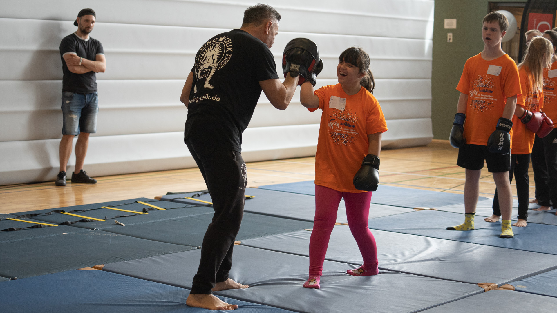 Foto: Teilnehmerin mit Boxhandschuhen führt Übungen mit einem Trainer aus.