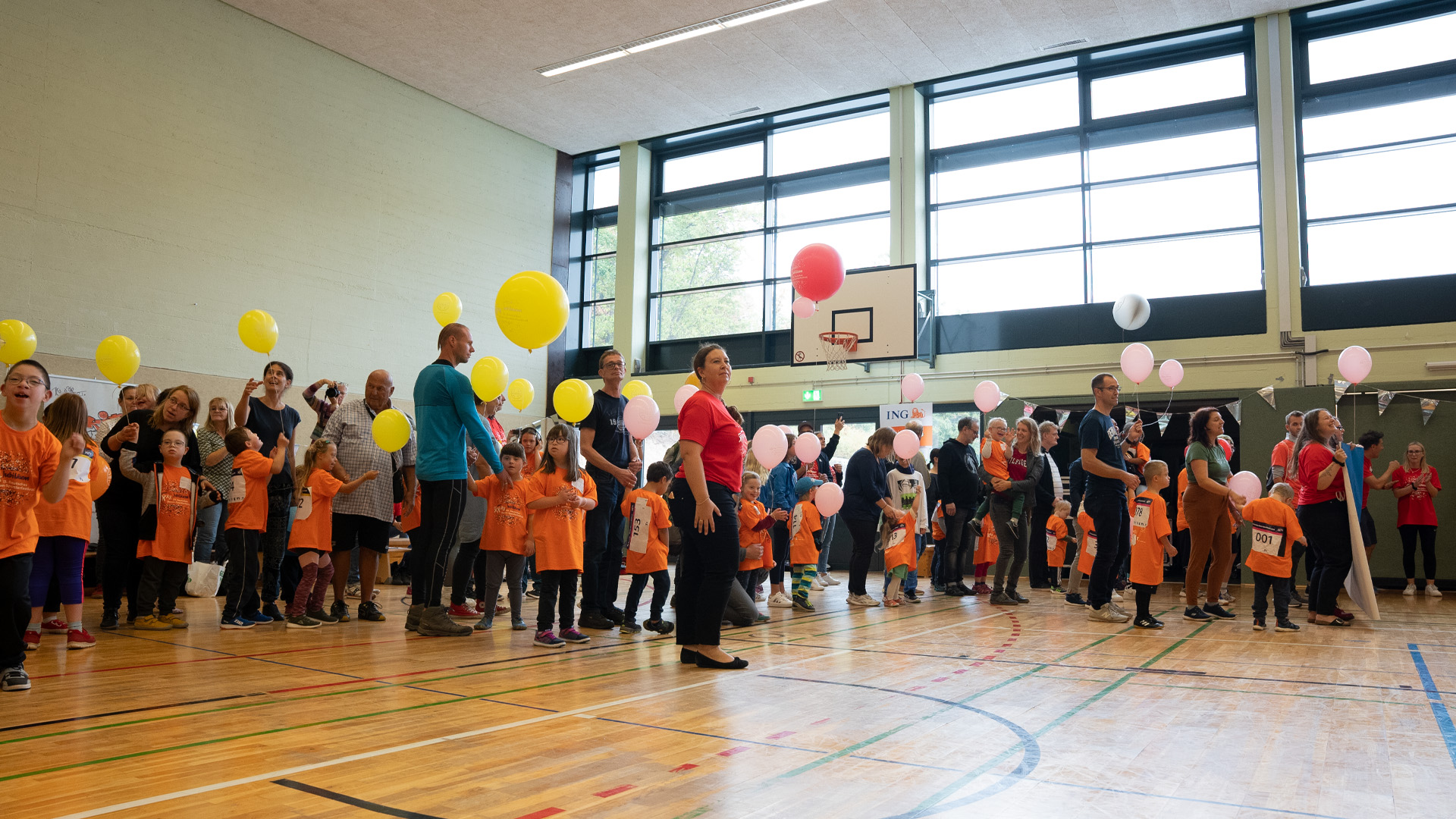 Foto: Große Gruppe von Teilnehmern und Helfern steht mit Ballons in einer Reihe in der Sporthalle.
